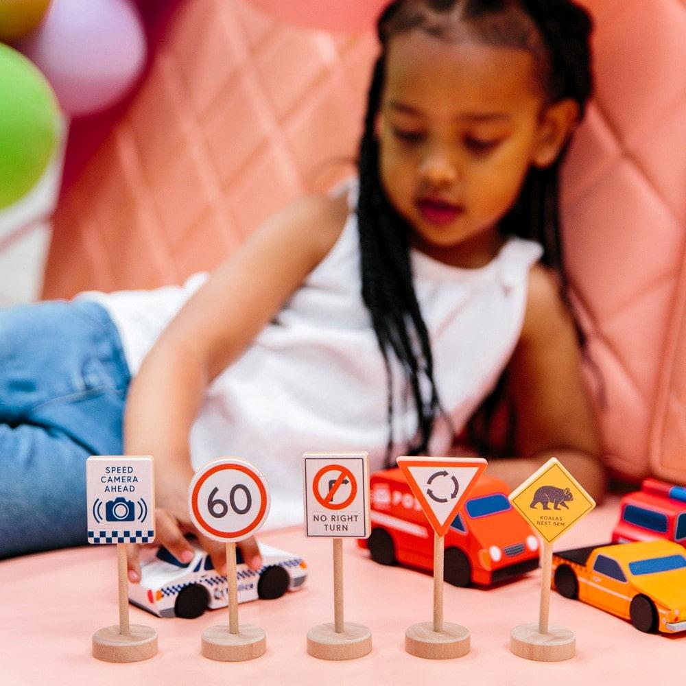 Make Me Iconic wooden Australian road sign toy set featuring 5 double-sided traffic signs with kangaroo, koala, and speed camera icons for imaginative car and city play.