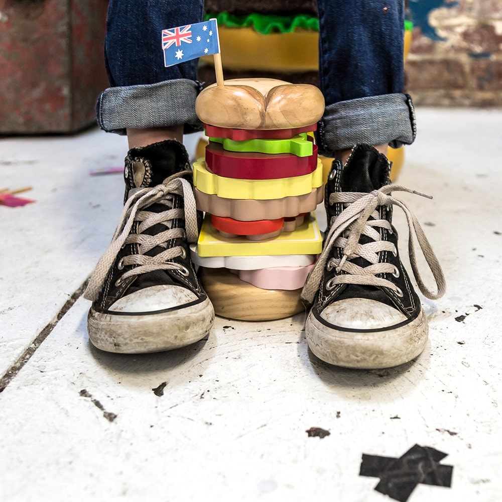 Wooden Aussie stacking burger toy for kids with colourful layers, mini flags, and chunky pieces—perfect for imaginative food play and motor skill development.