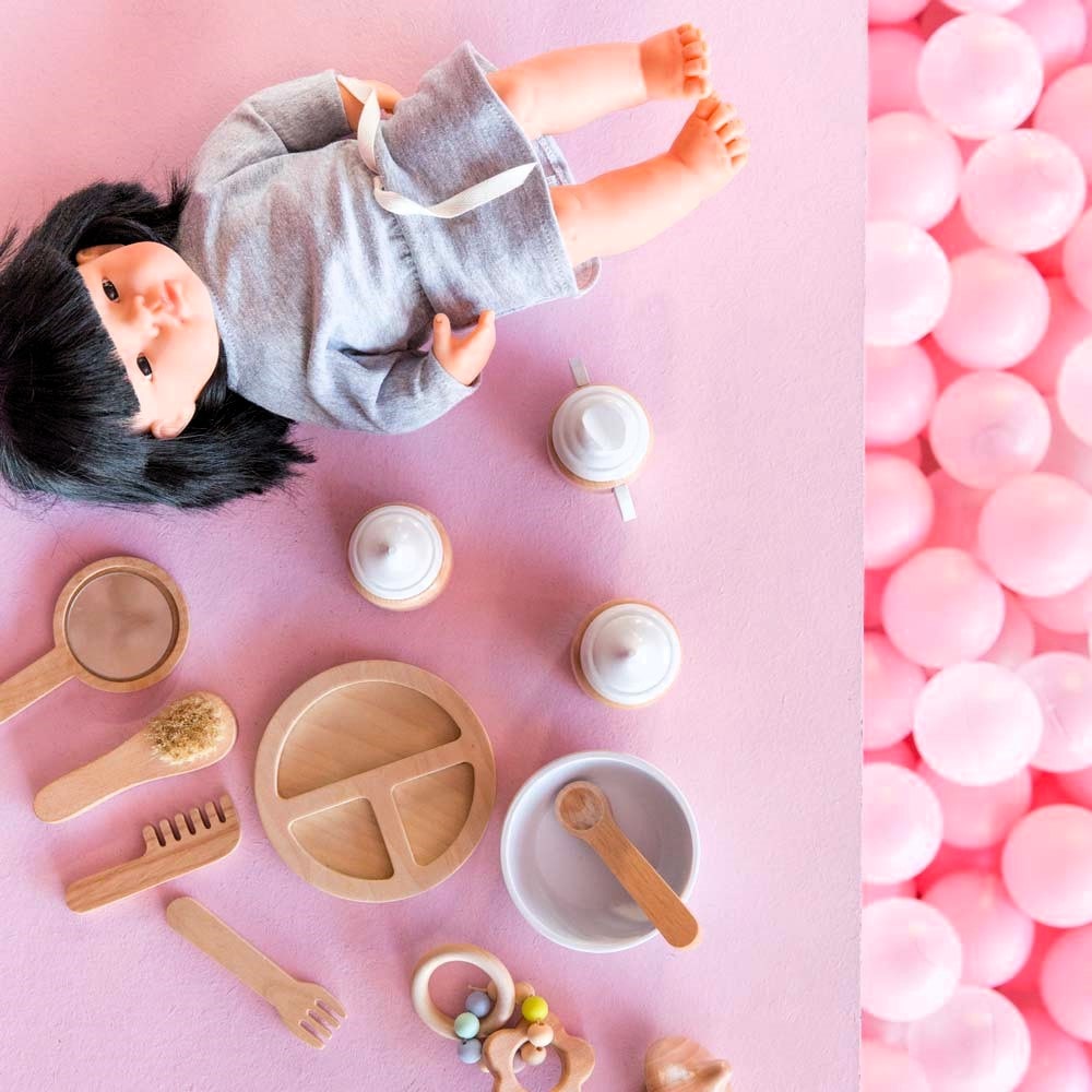 Make Me Iconic 11-piece wooden doll accessory kit with bottles, sippy cup, bowl, fork, spoon, brush with real bristles, comb, teether, and clip-on pacifier – perfect for pretend play.