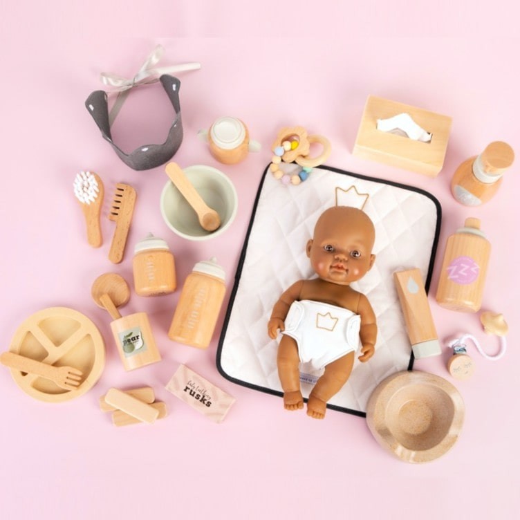 Make Me Iconic 11-piece wooden doll accessory kit with bottles, sippy cup, bowl, fork, spoon, brush with real bristles, comb, teether, and clip-on pacifier – perfect for pretend play.